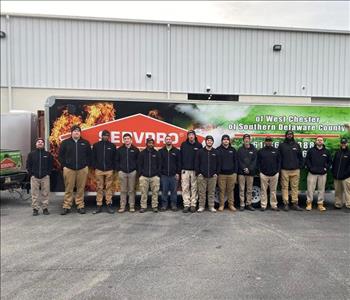 large group of men in SERVPRO uniforms standing in front of a truck