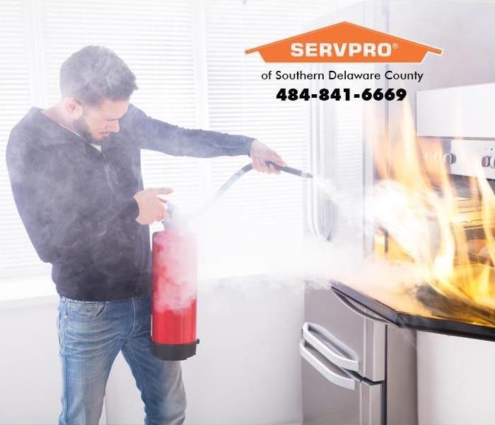 Man blowing a fire extinguisher into a flaming oven.
